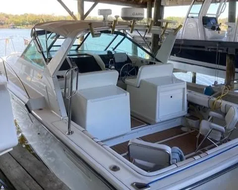 Slide: The Image of 1989 Tiara Yachts 3300 Open boat docked, featuring spacious seating and fishing rod holders. - 3