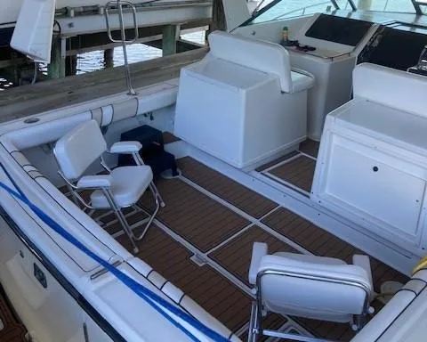 Slide: The Image of 1989 Tiara Yachts 3300 Open boat interior with white seating and wooden flooring. - 4