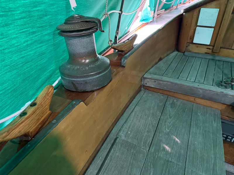 Slide: The Image of 1960 Concordia 39 Yawl interior with wooden seating and winch, under green tarp. - 17