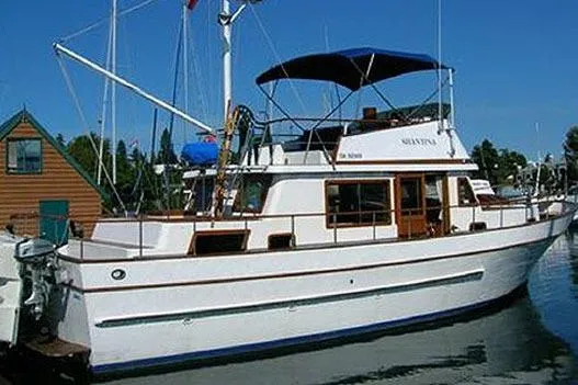 Slide: The Image of 1980 CHB Trawler boat docked, featuring classic design and blue canopy. - 15