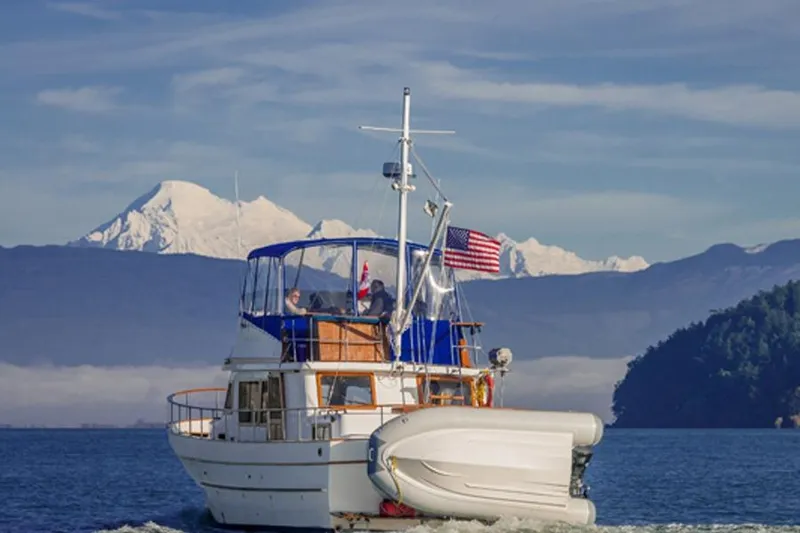 Slide: The Image of 1980 CHB Trawler cruising with mountain backdrop and American flag. - 16