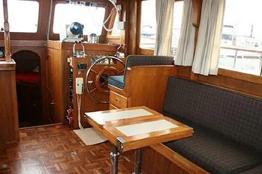 Slide: The Image of 1980 CHB Trawler interior with wooden helm, seating, and table. - 17