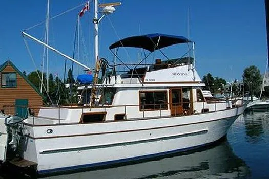 Slide: The Image of 1980 CHB Trawler boat docked at a marina with blue canopy and wooden accents. - 2