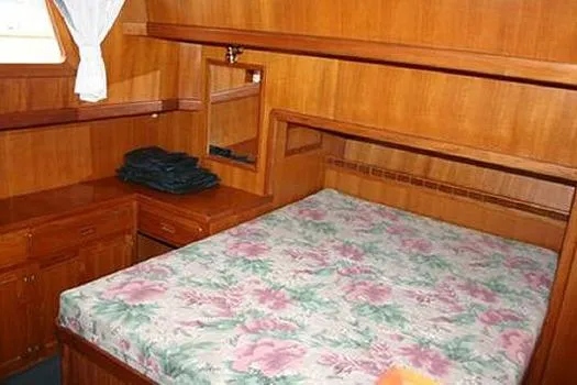 Slide: The Image of 1980 CHB Trawler cabin with floral bedspread, wooden interior, and small window. - 9