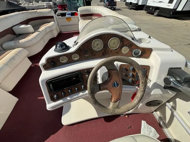 Slide: The Image of 2002 Godfrey Aqua Patio boat dashboard with steering wheel and control panel. - 16