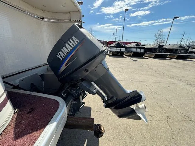 Slide: The Image of 2002 Godfrey Aqua Patio boat with Yamaha outboard motor in a parking lot. - 2