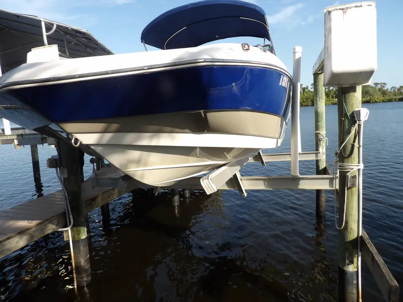 Slide: The Image of 2018 NauticStar 203DC Sport Deck boat on a lift by the water. - 1