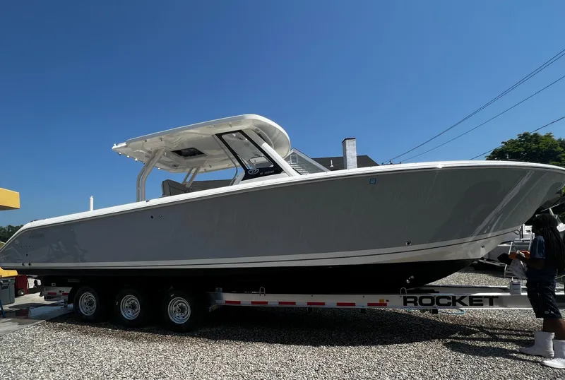 Slide: The Image of 2022 Pursuit S 328 Sport boat on a trailer under a clear blue sky. - 16