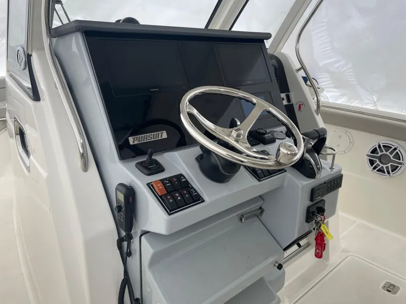 Slide: The Image of 2022 Pursuit S 328 Sport boat helm with steering wheel, controls, and electronic displays. - 30