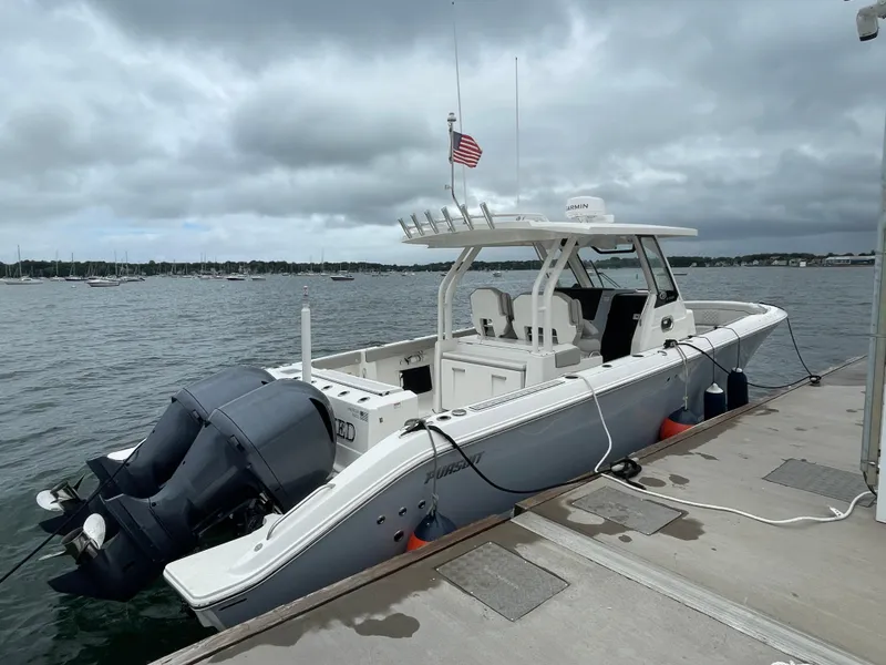 Slide: The Image of 2022 Pursuit S 328 Sport boat docked at marina with twin outboard engines. - 6