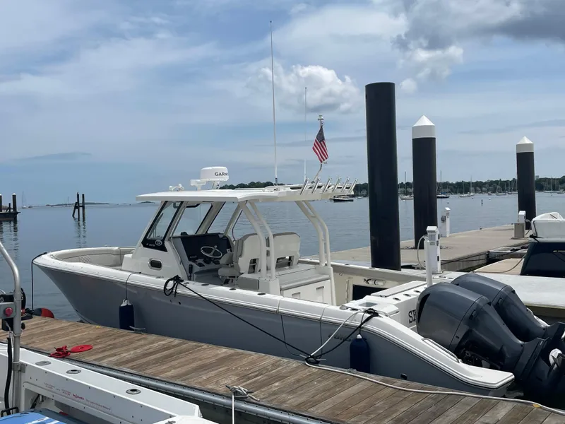 Slide: The Image of 2022 Pursuit S 328 Sport boat docked at a marina with calm waters. - 9
