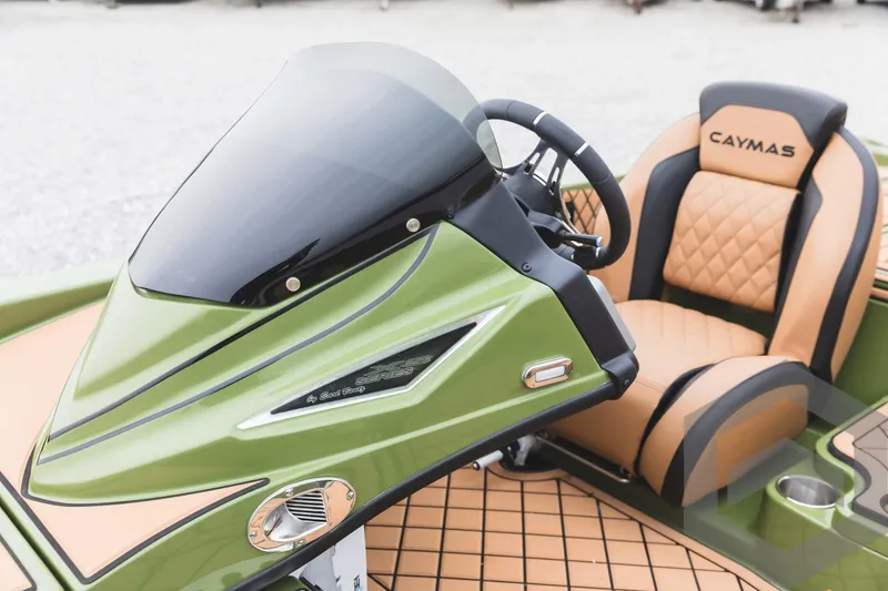 Slide: The Image of 2024 Caymas XS 20 Pro boat cockpit with green console and tan seats. - 23