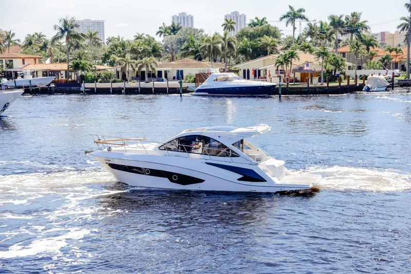 Slide: The Image of 2021 Evolve 400HT yacht cruising on a sunny waterfront with palm trees. - 1