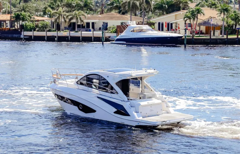 Slide: The Image of 2021 Evolve 400HT yacht cruising on a sunny waterfront with palm trees and houses. - 2