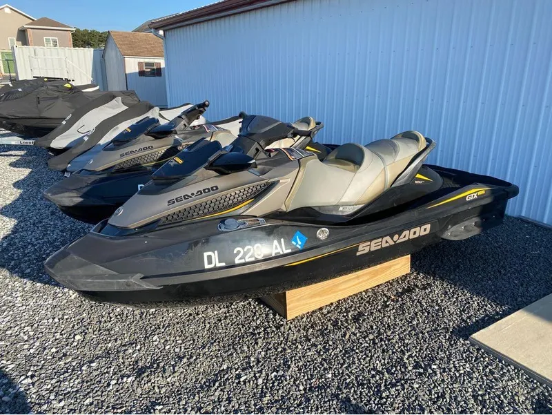 Slide: The Image of 2017 Sea-Doo GTX 155 jet skis parked on gravel near a white building. - 3
