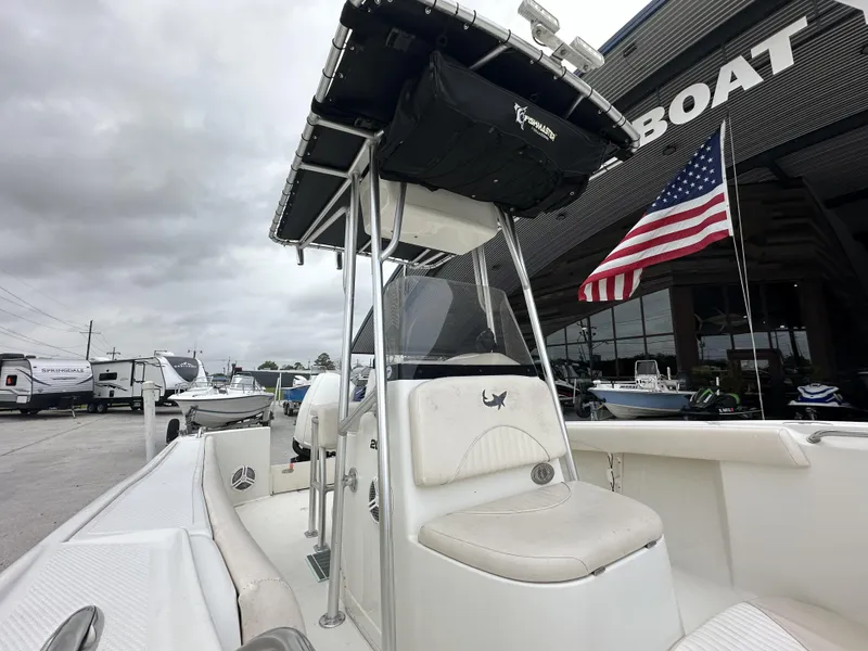 Slide: The Image of 2014 Mako 204 CC boat with T-top and American flag, parked at a dealership. - 4