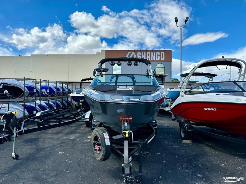 Slide: The Image of 2024 MasterCraft NXT21 boat on trailer at dealership, surrounded by other boats. - 2