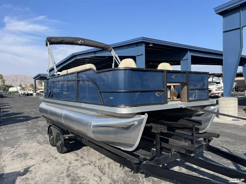 Slide: The Image of 2023 Crest 200 Classic Fish pontoon boat on a trailer in a marina. - 2