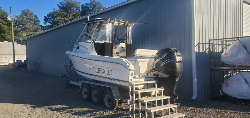 Slide: The Image of 2000 Robalo 2240 Walkaround boat on trailer beside a metal building. - 5