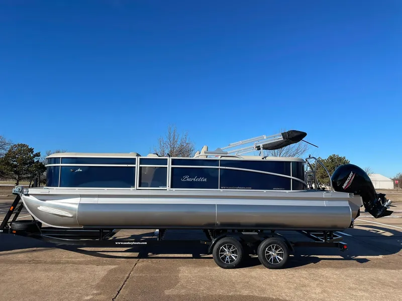 Slide: The Image of 2024 Barletta ARIA 22QC pontoon boat on a trailer under a clear blue sky. - 2