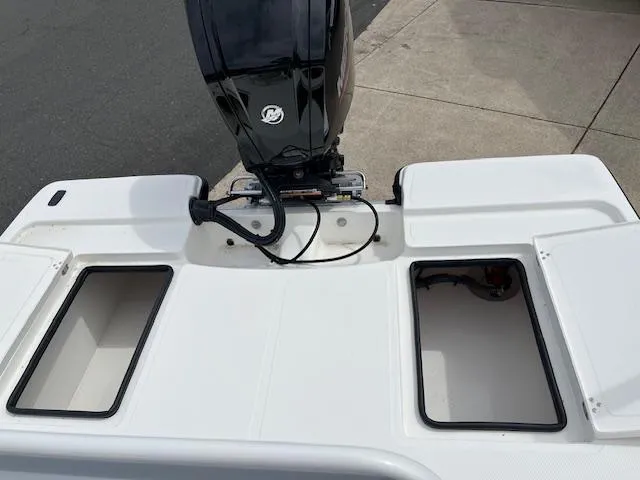 Slide: The Image of 2024 Mako 18 LTS boat stern with open storage compartments and outboard motor. - 4