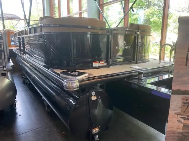 Slide: The Image of 2024 Regency 230 LE3 pontoon boat in showroom, black exterior, luxury seating. - 0