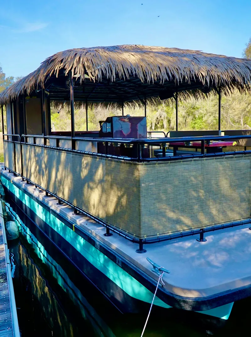 Slide: The Image of 2024 A&M Manufacturing BullDog 34 houseboat with a thatched roof docked on a sunny day. - 15