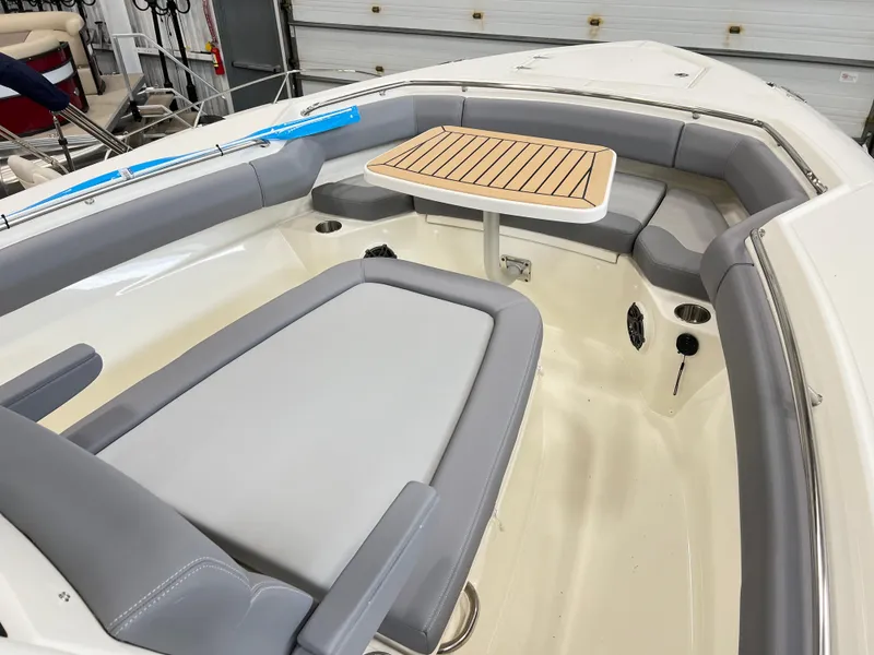 Slide: The Image of 2024 Boston Whaler 280 Outrage boat interior with cushioned seating and a wooden table. - 4