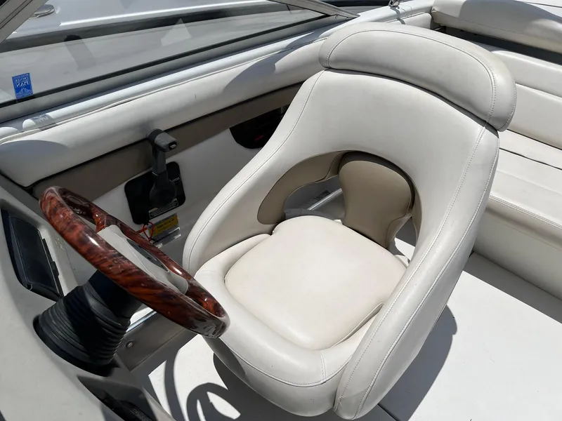 Slide: The Image of 2003 Four Winns 190 Horizon boat interior with white captain's chair and wooden steering wheel. - 10