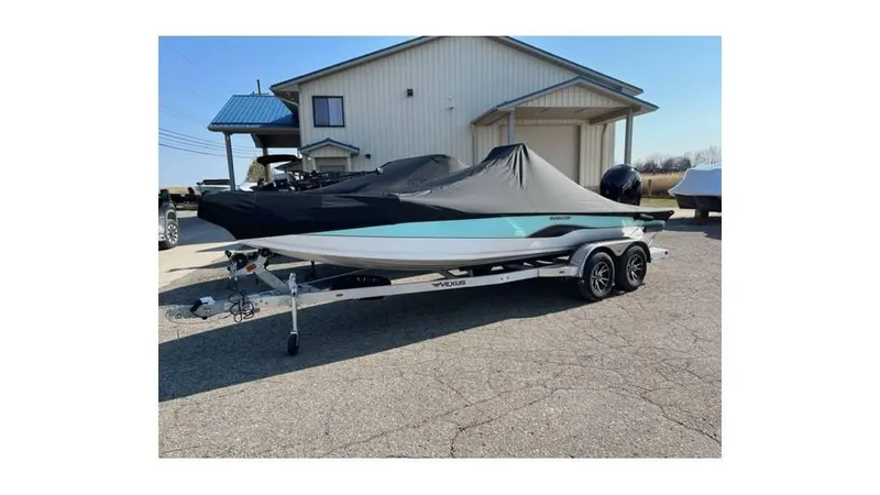 Slide: The Image of 2023 Vexus AVX 2180 CC boat with cover on trailer, parked outside a building. - 6