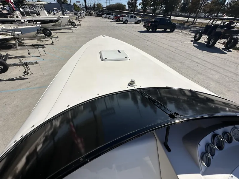 Slide: The Image of 1994 Wellcraft 2900 Sportboat bow view at a marina with other boats and vehicles. - 11