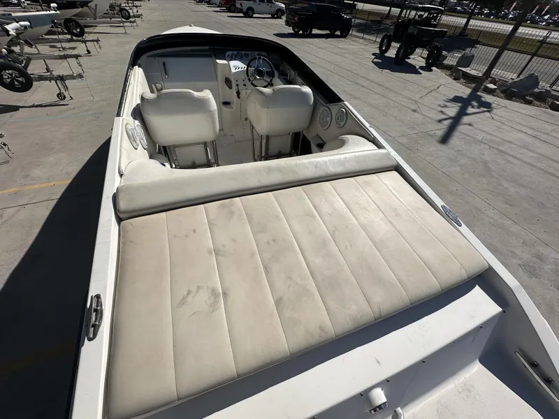 Slide: The Image of 1994 Wellcraft 2900 Sportboat interior with white seating and dashboard, parked on a concrete lot. - 12