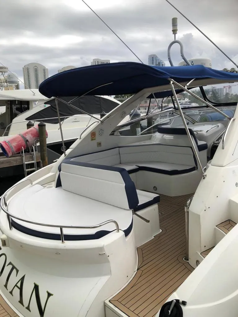 Slide: The Image of 2003 Sunseeker Portofino 46 yacht with blue canopy and white seating at marina. - 23