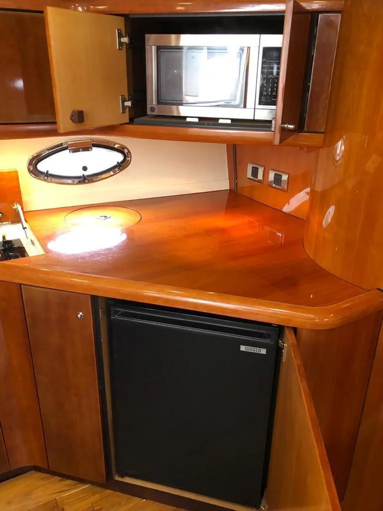 Slide: The Image of 2003 Sunseeker Portofino 46 yacht kitchen with microwave, fridge, and wooden cabinetry. - 36