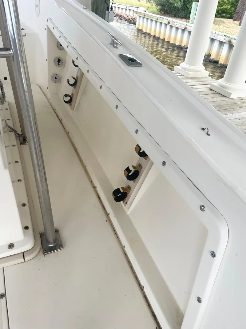 Slide: The Image of 1992 Mako 221 CC boat interior with rod holders and storage compartments. - 11