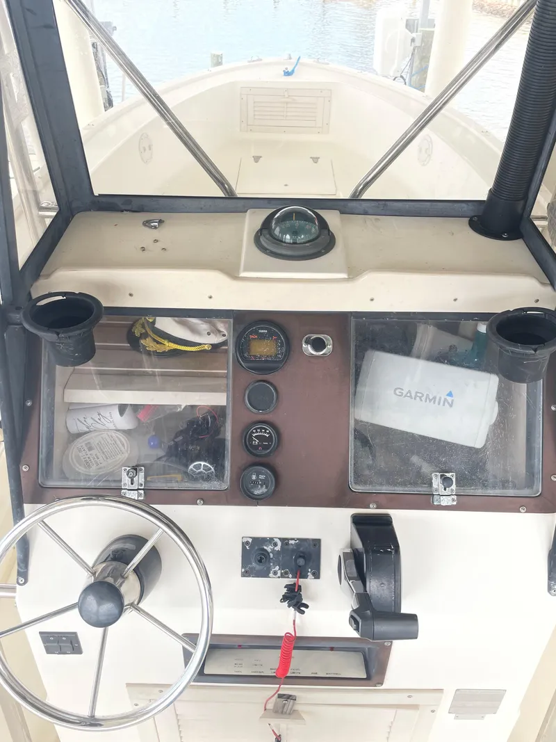 Slide: The Image of 1992 Mako 221 CC boat dashboard with steering wheel, gauges, and Garmin equipment. - 13