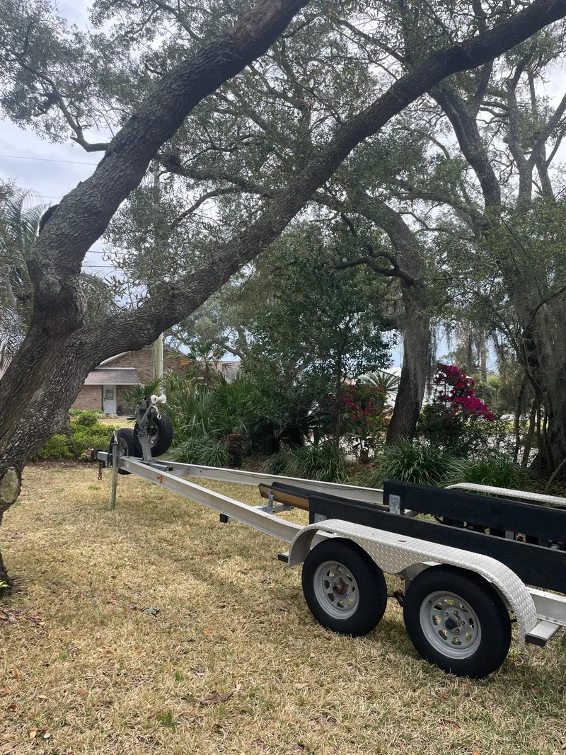 Slide: The Image of Trailer for 1992 Mako 221 CC boat parked in a yard with trees. - 19