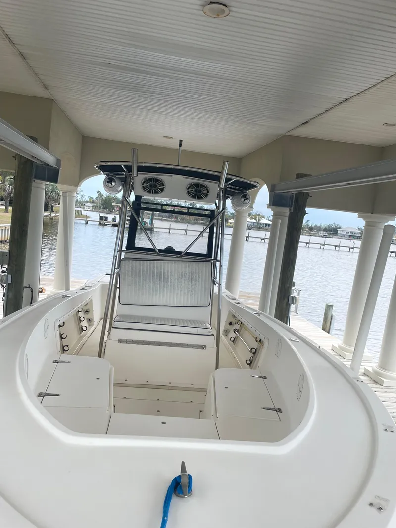Slide: The Image of 1992 Mako 221 CC boat docked under a covered pier with a scenic water view. - 6