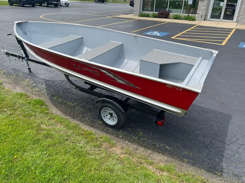 Slide: The Image of 2024 Lund WC-14 boat on a trailer in a parking lot. - 2
