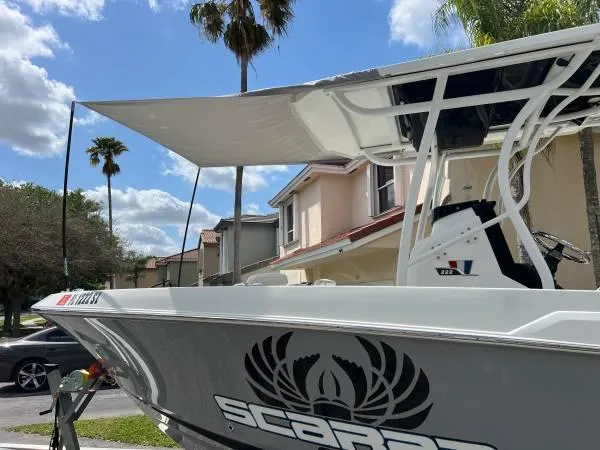 Slide: The Image of 2021 Wellcraft 222 Fisherman boat with Scarab logo, parked in a residential area. - 2