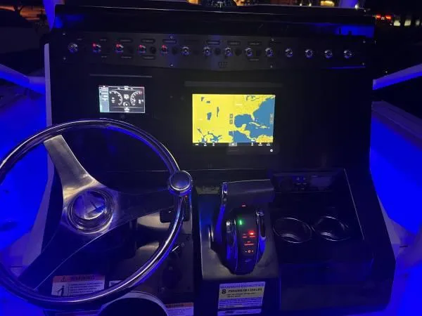 Slide: The Image of 2021 Wellcraft 222 Fisherman boat dashboard with navigation and control systems illuminated at night. - 7
