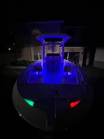 Slide: The Image of 2021 Wellcraft 222 Fisherman boat illuminated with blue, green, and red lights at night. - 8