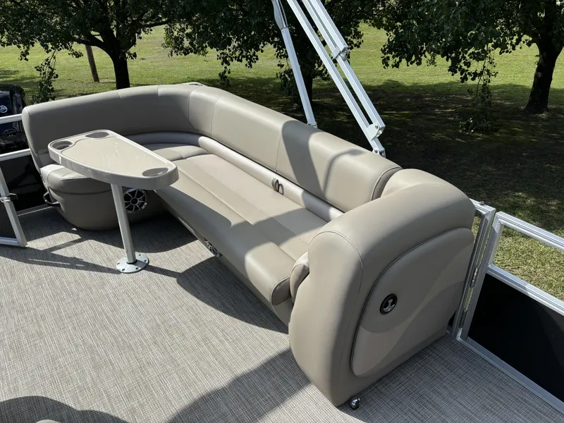 Slide: The Image of 2024 Ranger 200C boat interior with beige seating and table, surrounded by trees. - 12