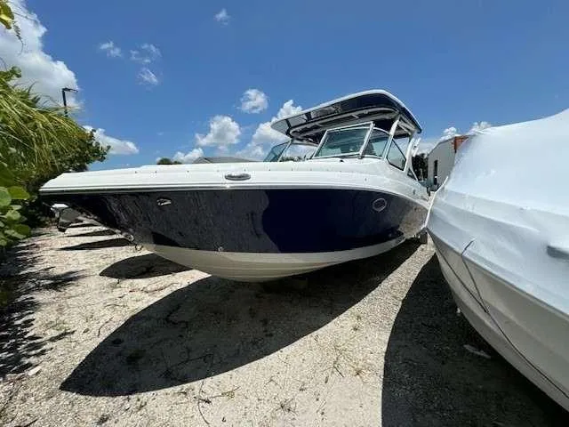 Slide: The Image of 2024 Crownline 280 DC boat on sandy shore under clear blue sky. - 1