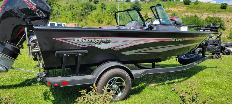 Slide: The Image of 2024 Ranger VS1782SC Reata boat on trailer, black with red accents, parked on grass. - 0