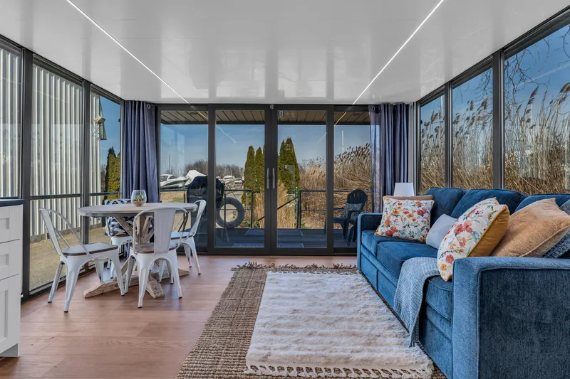 Slide: The Image of Modern Waterlodge Apart EL 2024 interior with cozy living area, dining table, and large windows. - 13