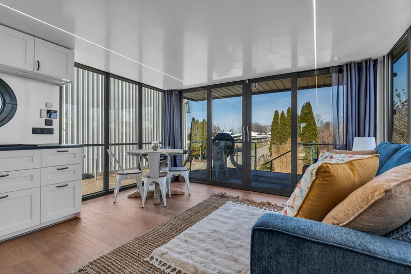 Slide: The Image of Modern Waterlodge Apart EL 2024 interior with cozy seating, dining area, and large windows. - 14