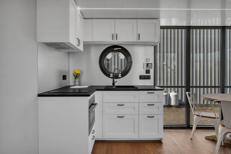 Slide: The Image of Modern kitchen in 2024 Waterlodge Apart EL with white cabinets and black countertops. - 15