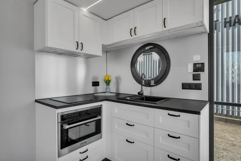 Slide: The Image of Modern kitchen in 2024 Waterlodge Apart EL with white cabinets and black countertops. - 16