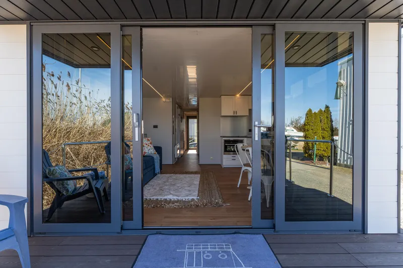 Slide: The Image of 2024 Waterlodge Apart EL interior view through glass doors, featuring modern living space. - 24